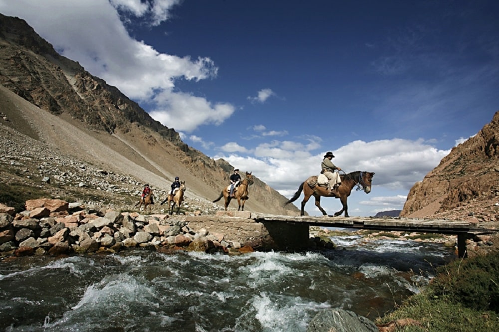Horseback riders crossing bridge over river